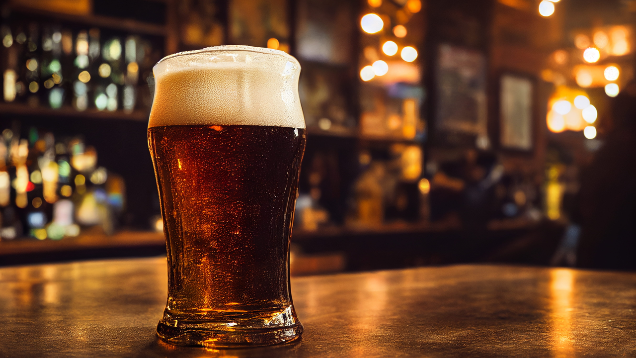 A pint of lager resting on a polished wooden bar counter.